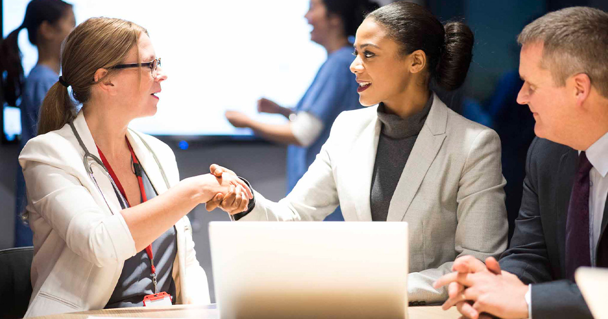 Businesspeople shaking hands in front of a laptop