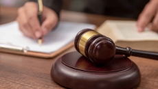 Person signing a document with a gavel on the table