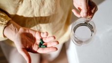 Person holding pills and a glass of water