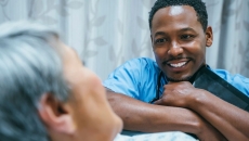 Healthcare provider sitting at a patient's bedside