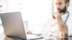 Healthcare provider sitting at a desk and looking at a computer