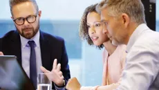 Businesspeople sitting around a laptop