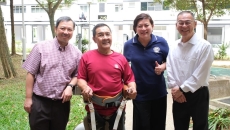 An elderly person wearing an assistive robot developed at NTU Singapore, together with its developers