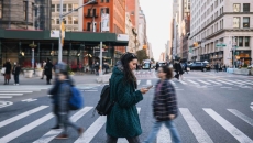 People walking across a crosswalk in the streets of a large city