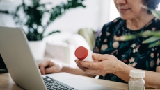 Person on a computer holding medication