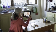 Person sitting at a table looking at a tablet