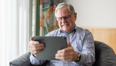 An elderly person using a digital tablet to consult with a doctor online