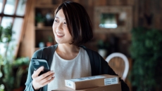 Person standing in their living room next to a lot of boxes while holding a phone