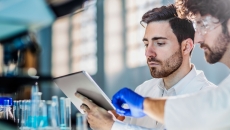 Two workers in a laboratory looking at a tablet