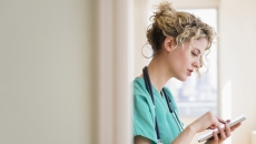 Healthcare provider standing in a doorway while looking at a tablet