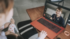 Two people sitting on a couch while looking at a laptop on a coffee table that is open with a healthcare provider on the screen