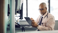 A doctor using a tablet in a patient exam room