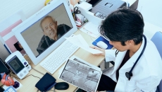 A doctor looking at imaging results while consulting with a patient on his laptop