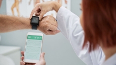 A doctor showing patient how to synchronize health app in smartphone and smartwatch