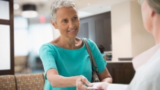 A woman handing her insurance card to a healthcare worker