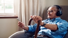 A person wearing headphones, using a smartphone and wearing a watch in the home