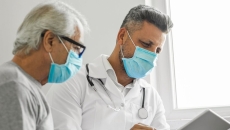 An older man and doctor looking at results on a tablet.