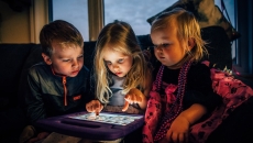 Three children playing on a digital tablet