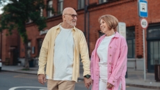 A senior couple holding hands while walking down the street