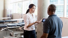 A medical professional uses a digital tablet to explain brain injury and recovery to a person after his stroke.