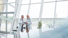 Two healthcare professionals standing in a large room with windows