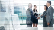Four people standing in a room with two of them shaking hands
