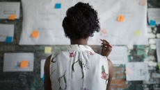 A woman at work standing in front of a wall with papers and planning documents