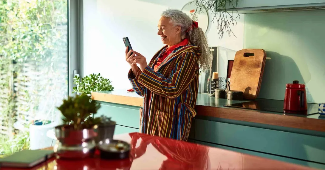 Person standing in their kitchen looking at the phone