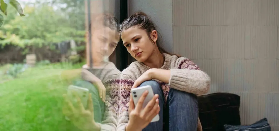 Person sitting next to a window who looks depressed