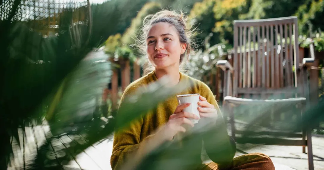 Person sitting outside while drinking a cup of coffee