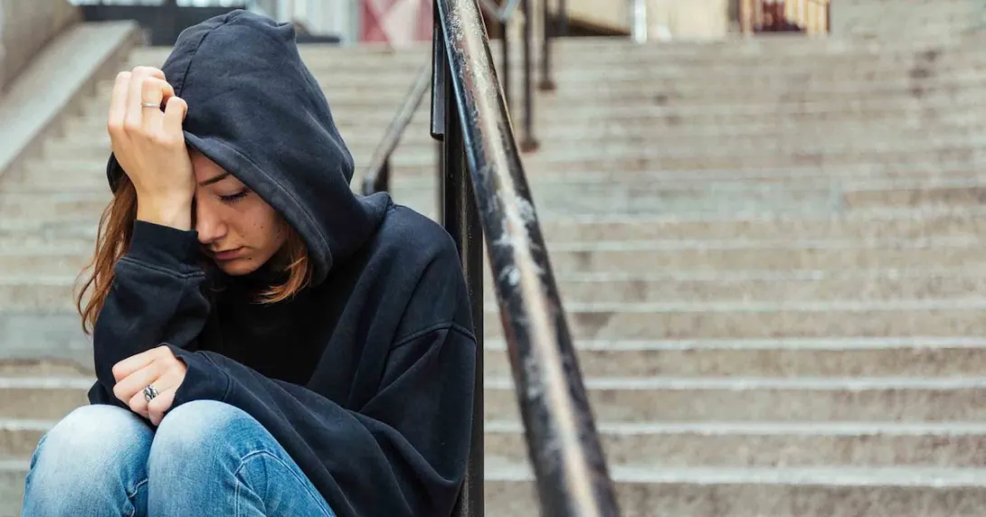 Person sitting on steps with their head in their hands