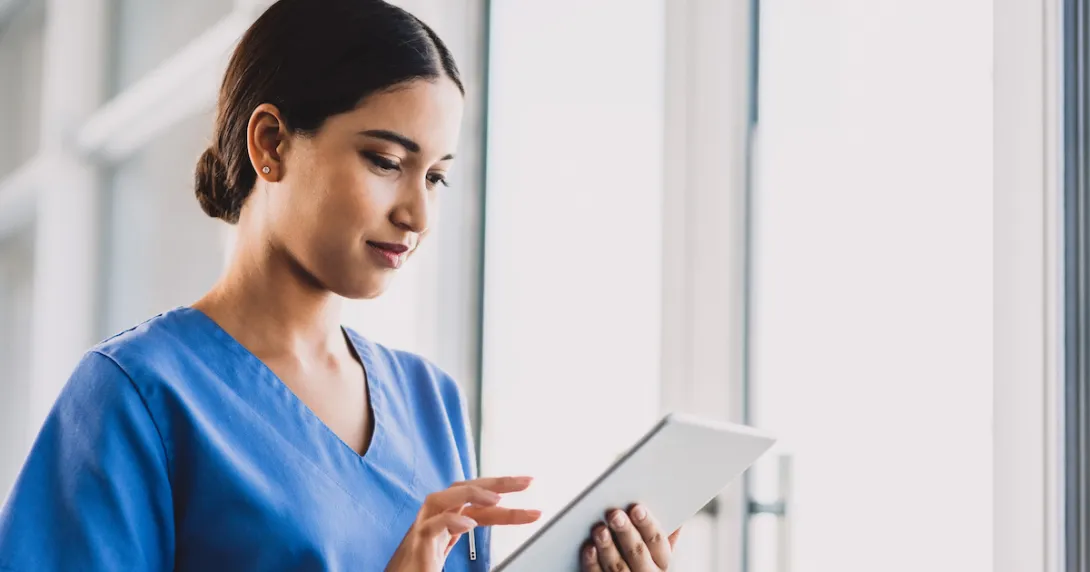 Nurse standing in a hallway holding a tablet