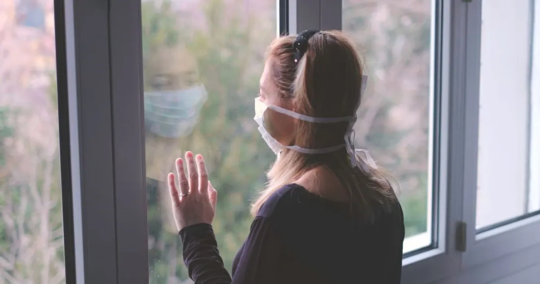 Person wearing mask looking out window