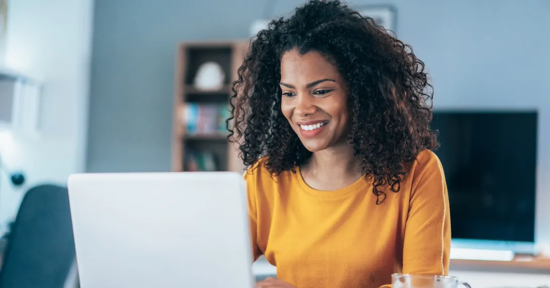Person sitting at a computer looking at the screen while smiling