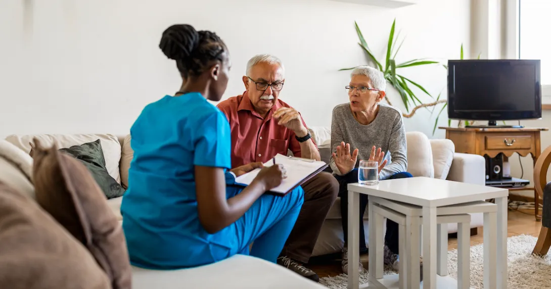 Two people sitting on a couch talking to a healthcare provider who is sitting on a different couch