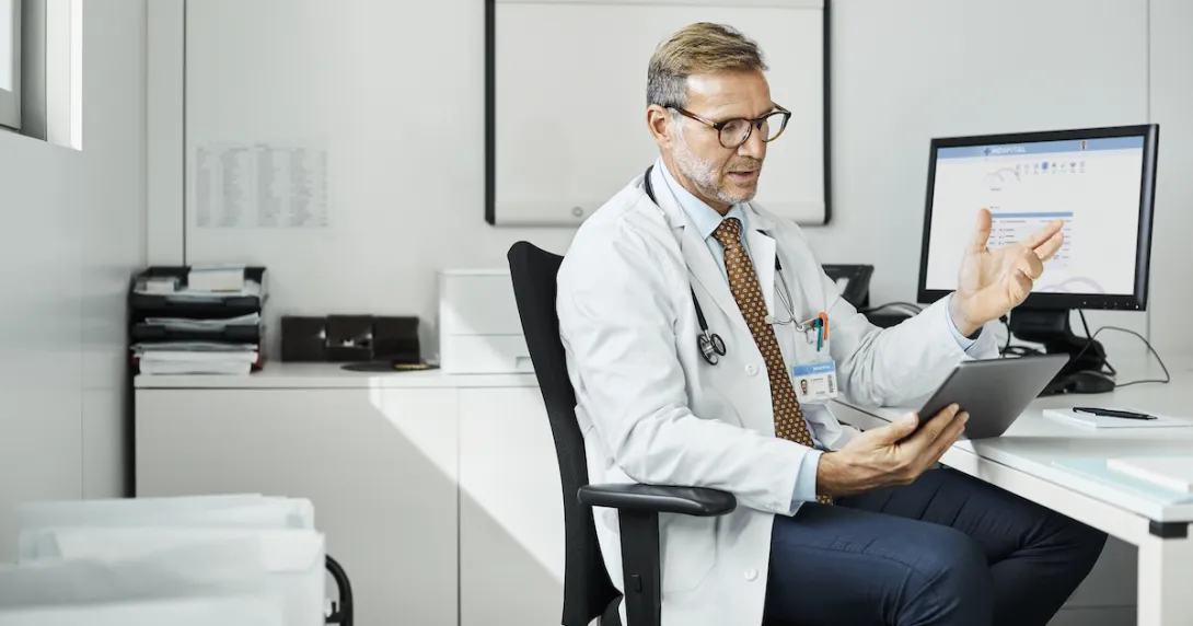 Healthcare provider sitting at a desk while talking to someone on the computer