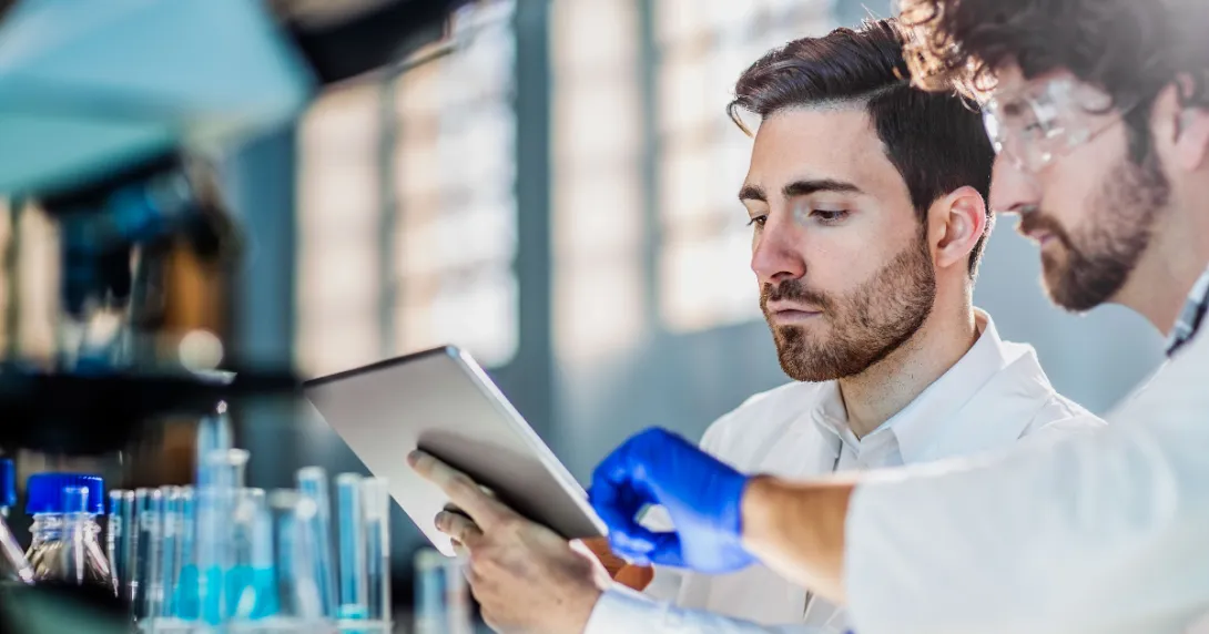 Two scientists in a lab looking at a tablet