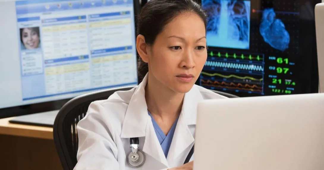 Healthcare professional sitting at a desk with many computers around them