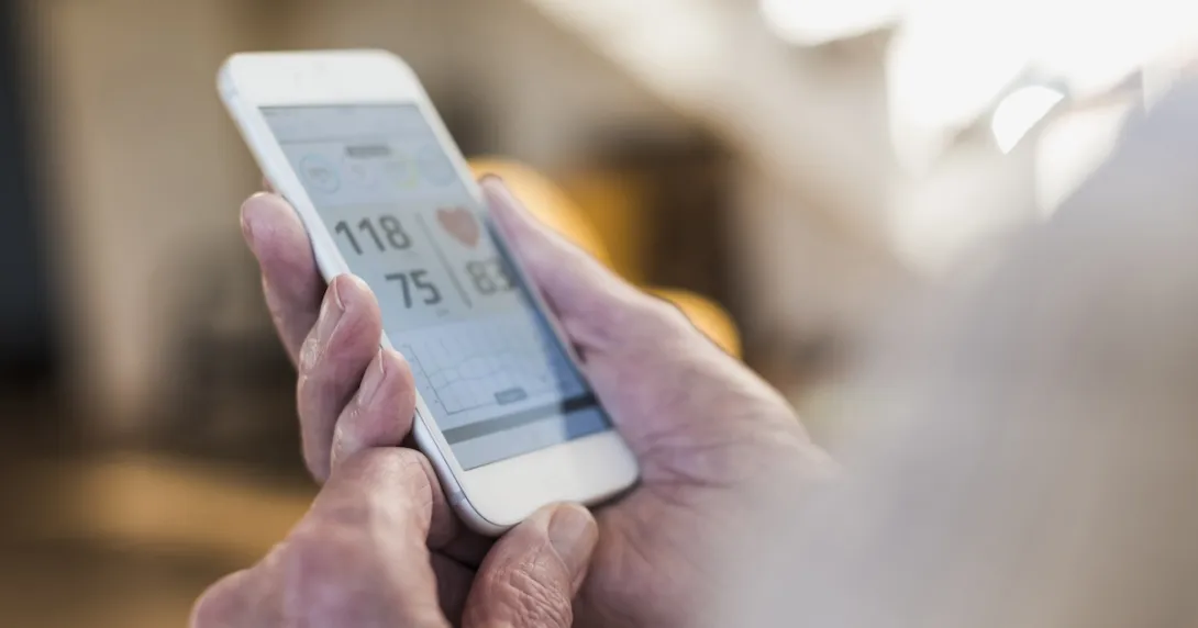 A person holding a phone showing a blood pressure reading