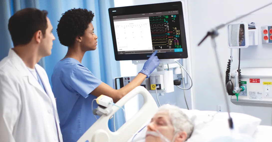 Providers using the new patient monitor next to a bed where a patient is sleeping