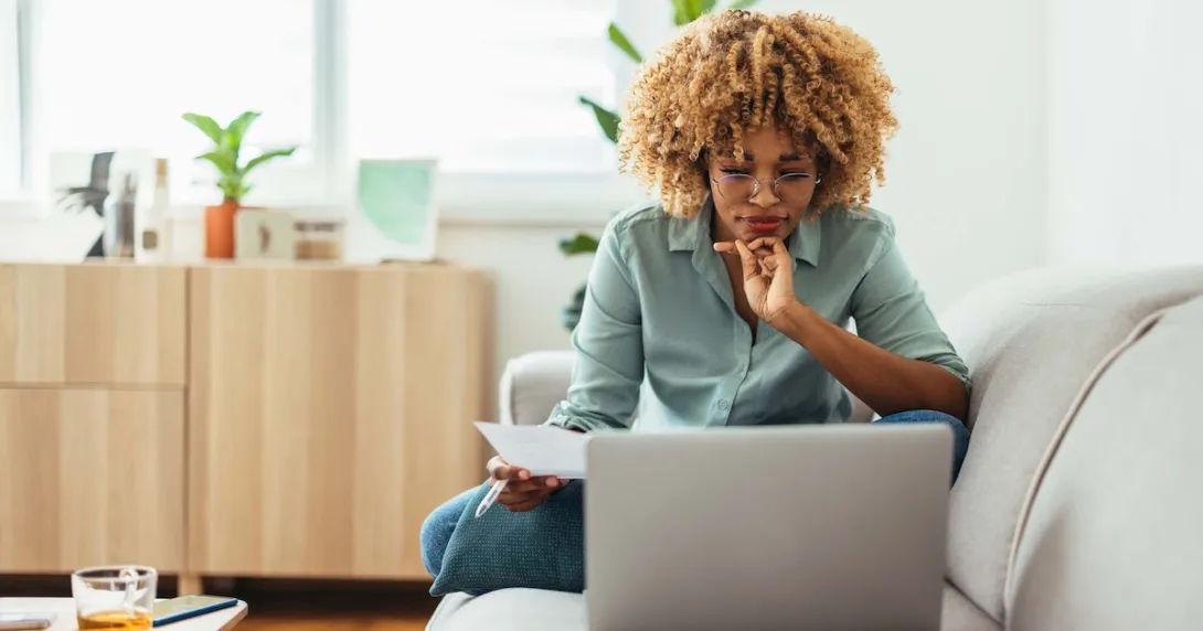Individual sitting on a couch and looking at a computer