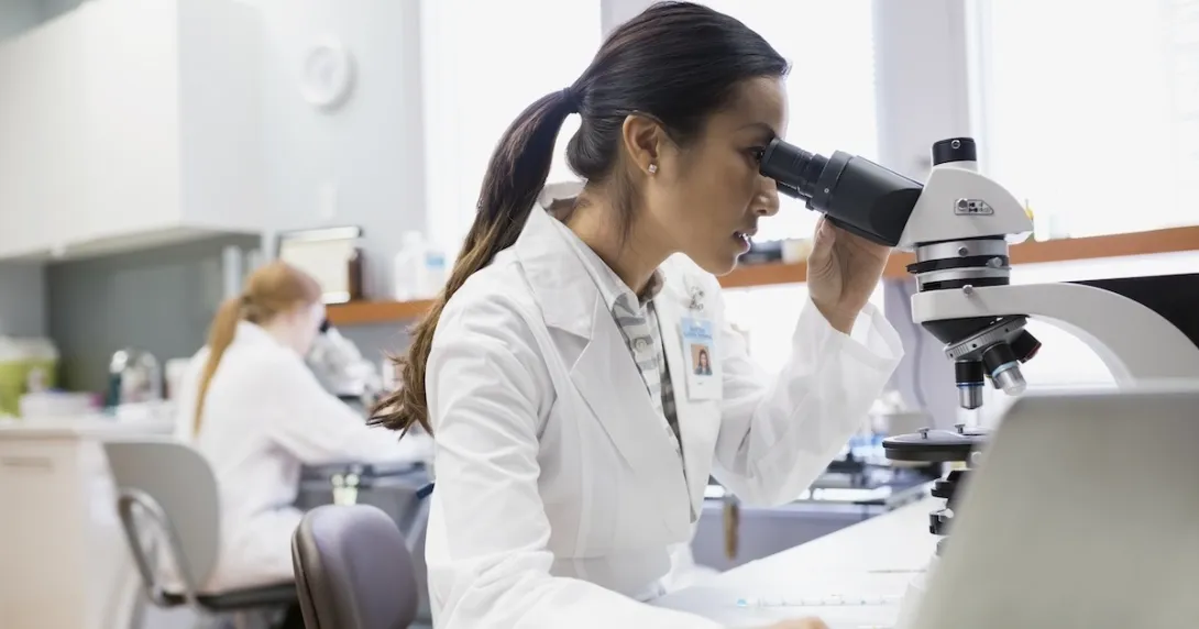 Health care practitioner looking through a microscope