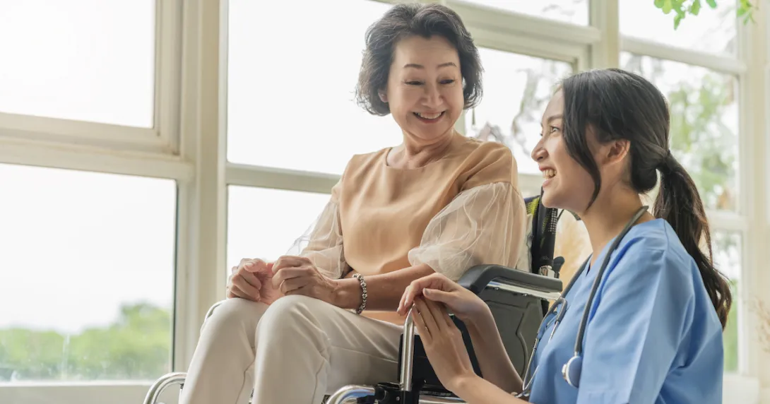 A caregiver sitting beside a senior patient in a wheelchair
