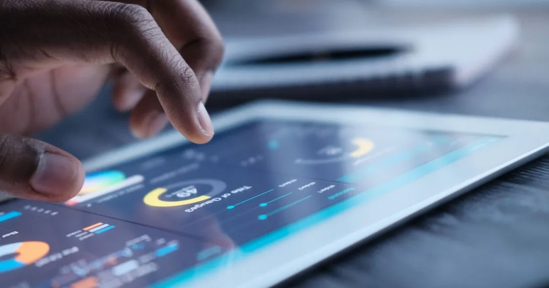 A close up of a person using a tablet displaying data and charts