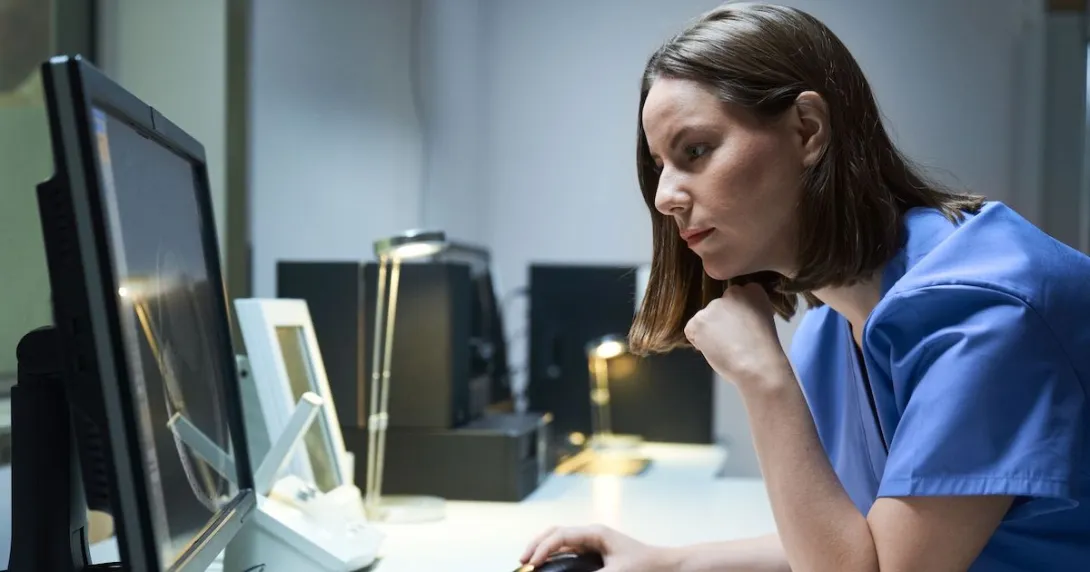 A doctor looking at a MRI results on a desktop computer