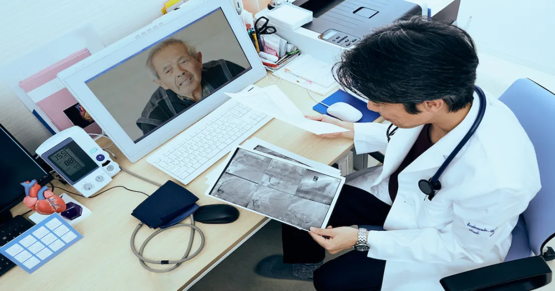 A doctor speaking with a patient using telehealth and looking at imaging results.