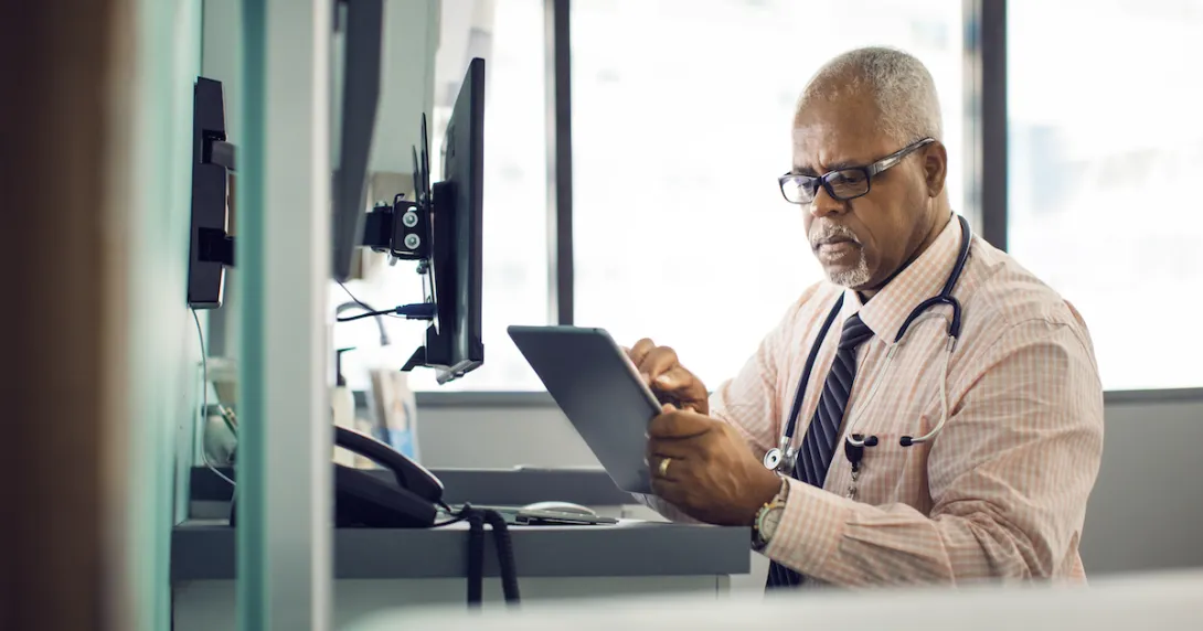 A doctor using a tablet in a patient exam room