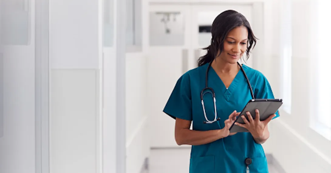 Healthcare provider wearing scrubs with a stethoscope around their neck while walking down the hallway of a health center