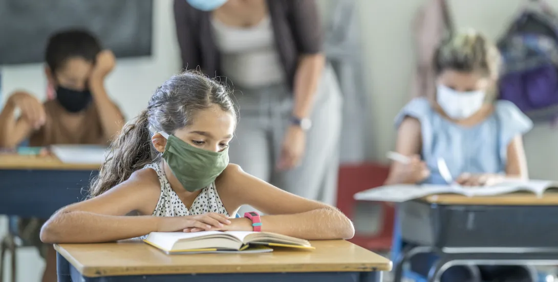 A student in school reading while wearing a mask