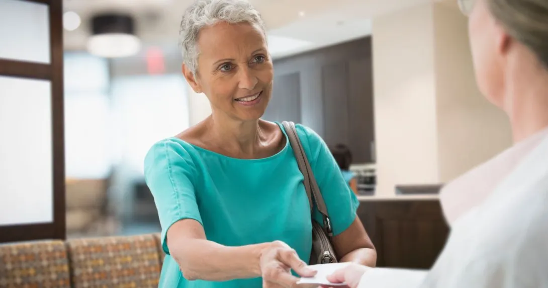 A woman handing her insurance card to a healthcare worker
